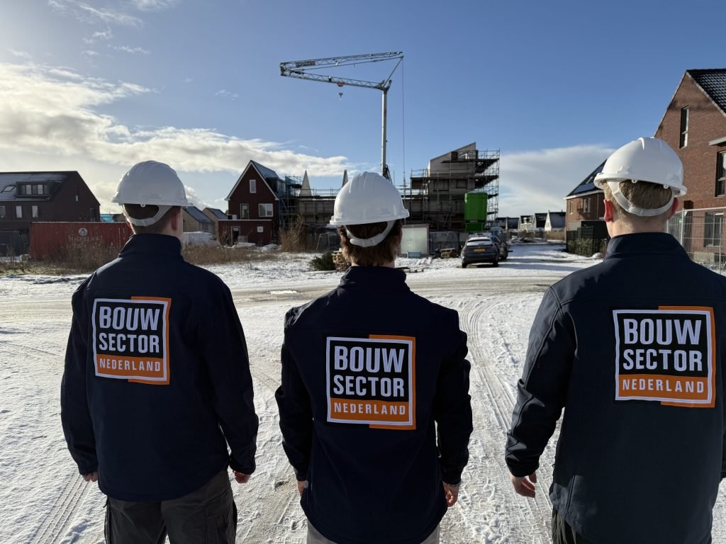 Vakmensen van Bouwsector Nederland met witte helm kijken naar bakstenen gevels van nieuwe huizen